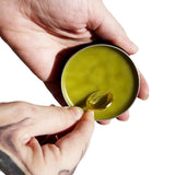 Urb Apothecary Repair Salve being scooped from tin — nourishing botanical balm designed to support tattoo healing, reduce inflammation, and protect sensitive skin