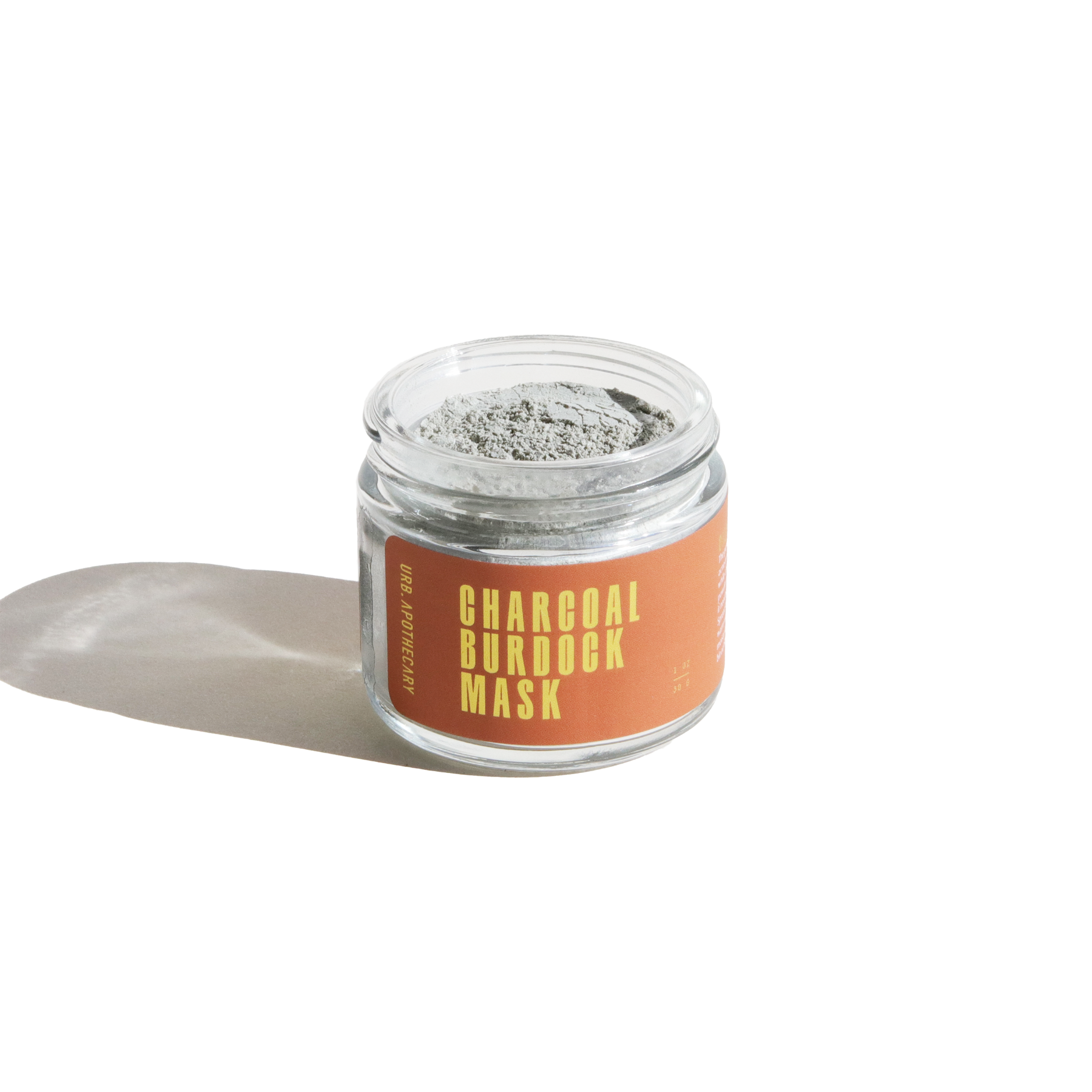 Glass jar of Urb Apothecary Charcoal Burdock Mask with earthy orange label, filled with detoxifying clay powder for clarifying and calming blemish-prone skin