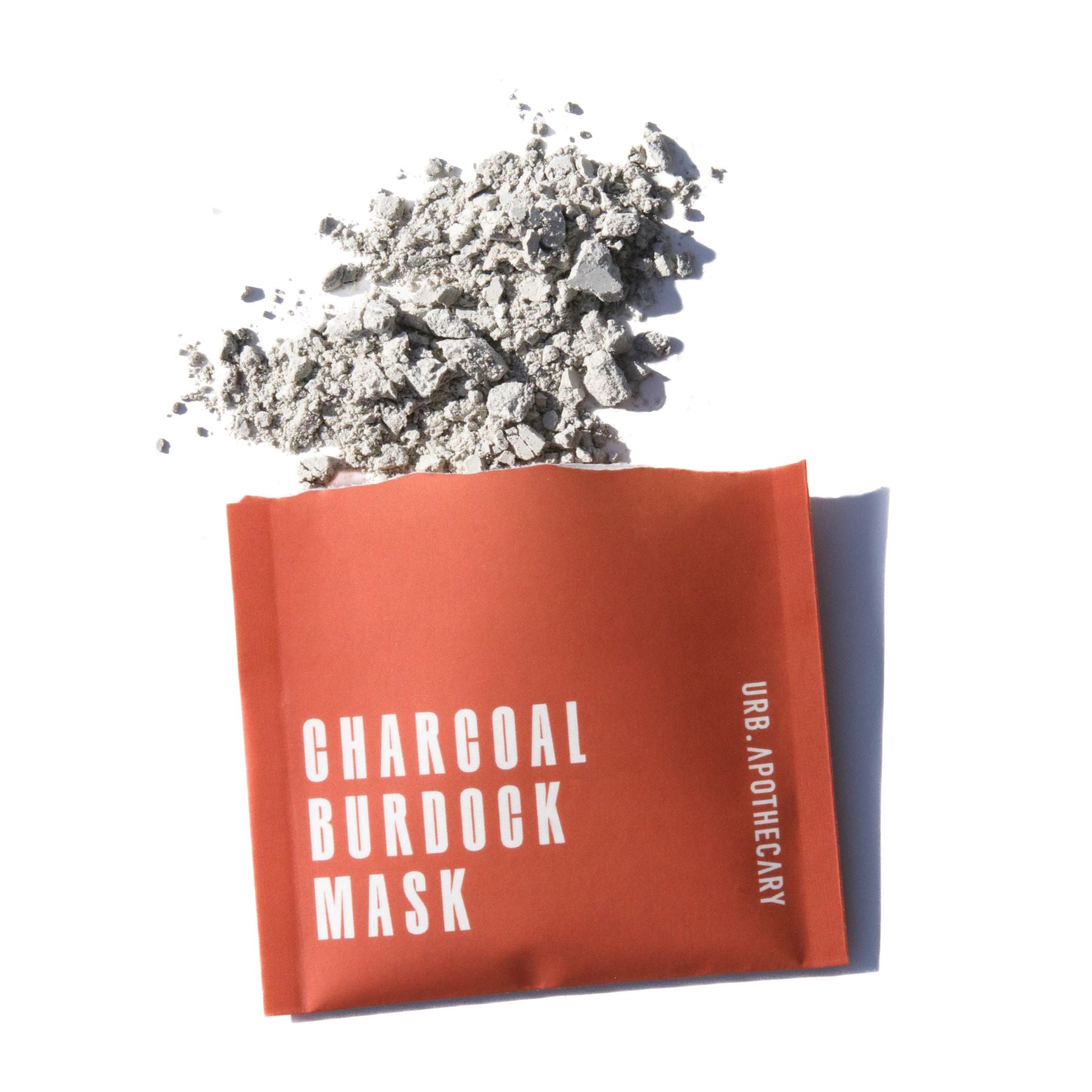 eco-friendly biodegradable beauty packaging Single-use packet of Urb Apothecary Charcoal Burdock Mask with powder spilling out — purifying clay and charcoal blend for oily or blemish-prone skin