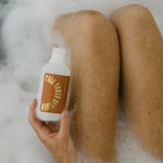 Person relaxing in a bubble bath holding Urb Apothecary’s Palo Santo Cleanser, capturing a serene self-care moment with plant-powered skincare